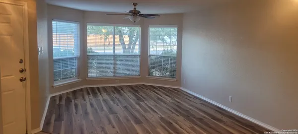 a view of an empty room with wooden floor and a window