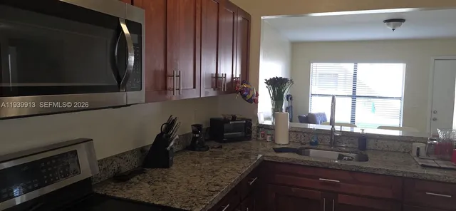 a kitchen with granite countertop a sink a stove and cabinets