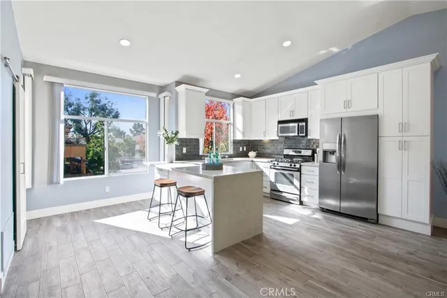 a kitchen with stainless steel appliances granite countertop a refrigerator a stove top oven a sink dishwasher and a refrigerator with wooden floor
