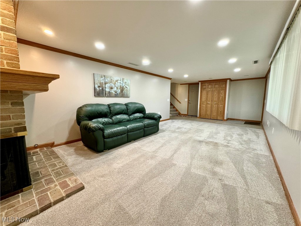 2180 Portage Line Road Uniontown, OH 44685 - Photo 20 of 25 Living room with crown molding, brick wall, a brick fireplace, and light carpet