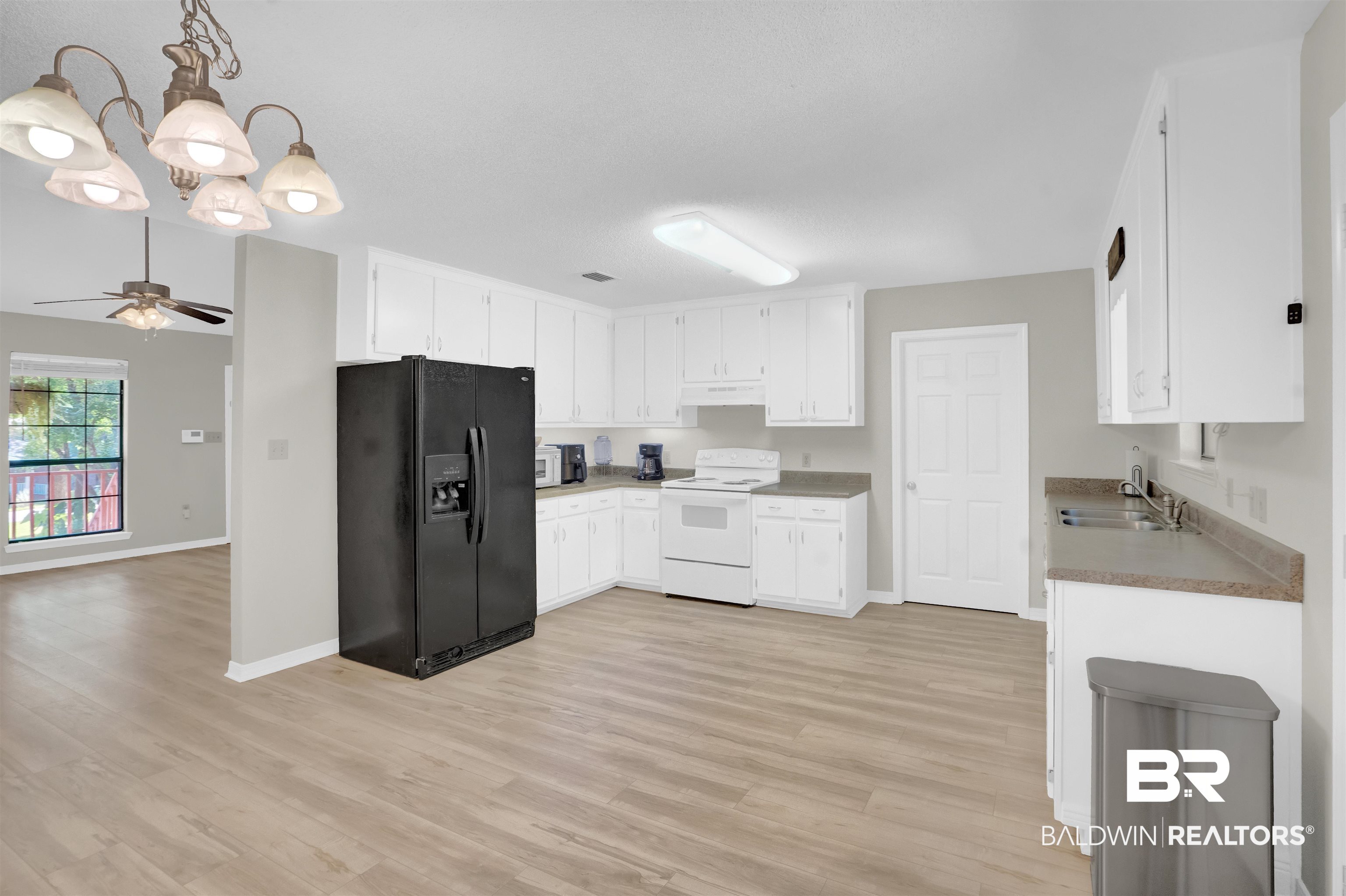 30871 Stanton Road Spanish Fort, AL 36527 - Photo 14 of 35 Kitchen featuring light hardwood / wood-style flooring, ceiling fan with notable chandelier, white cabinetry, sink, and white appliances