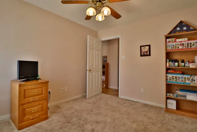an empty room with chandelier fan and windows