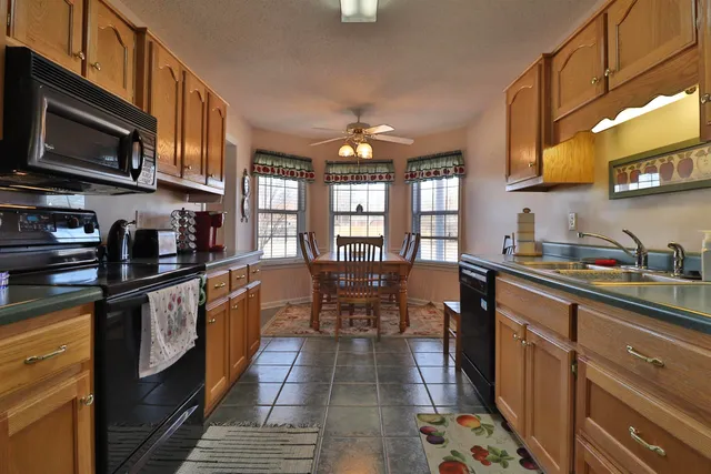 a kitchen with stainless steel appliances granite countertop a stove top oven a sink dishwasher a dining table and chairs with wooden cabinets