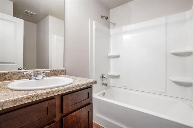 a bathroom with a granite countertop tub sink and mirror