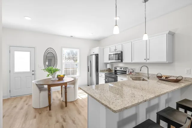 a kitchen with granite countertop a stove a sink a counter space and dining table with wooden floor