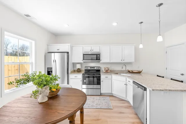 a kitchen with a white center island a sink cabinets and stainless steel appliances