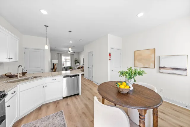 a kitchen with stainless steel appliances a white table chairs and white cabinets