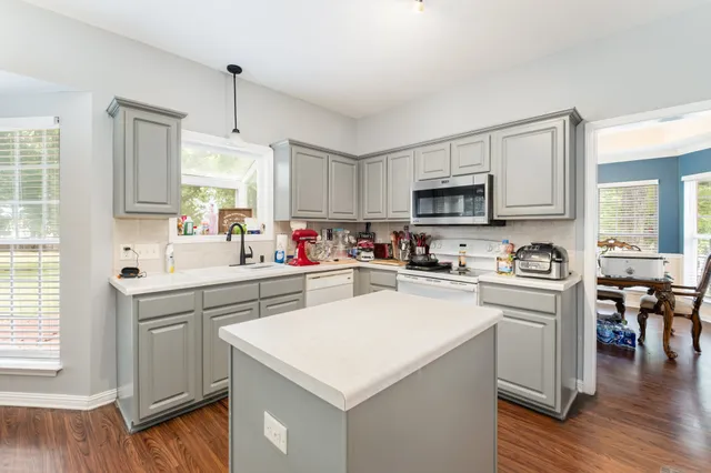 a kitchen with a sink a stove top oven a refrigerator cabinets and wooden floor