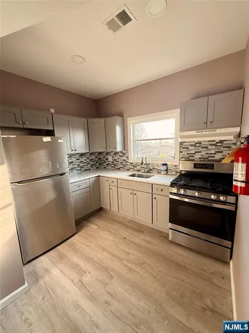 a kitchen with stainless steel appliances granite countertop a stove a sink dishwasher a refrigerator and a stove