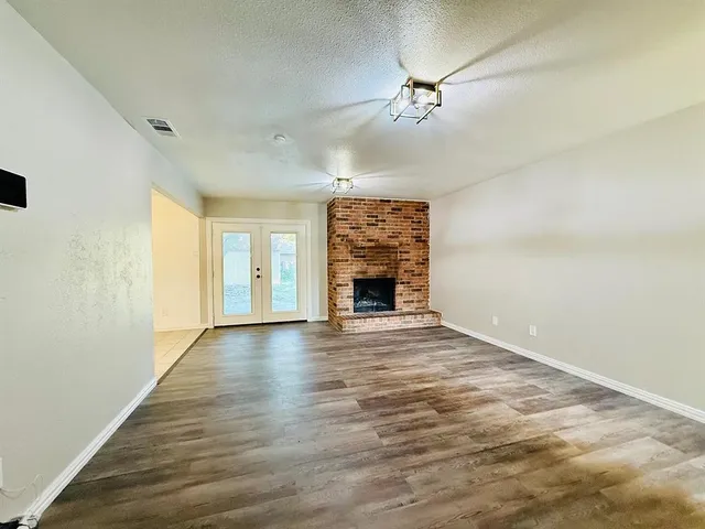 a view of empty room with wooden floor and fireplace