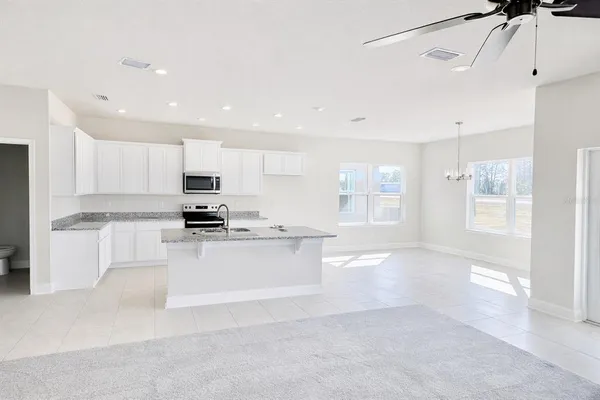 a kitchen with stainless steel appliances granite countertop a refrigerator sink and white cabinets