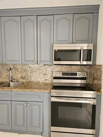 a kitchen with granite countertop white cabinets appliances and a sink