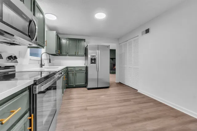 a kitchen with stainless steel appliances granite countertop a sink a stove top oven and wooden floor