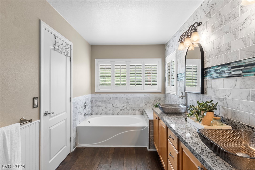 708 Vortex Avenue Henderson, NV 89002 - Photo 33 of 71 Relax in a soaking tub or refresh in a well-appointed vanity area featuring granite counters and elegant tile work.