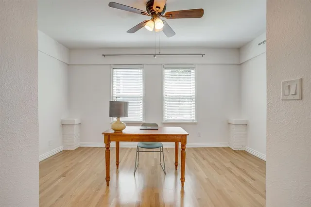 a dining room with wooden floor a chandelier fan a wooden table and chairs