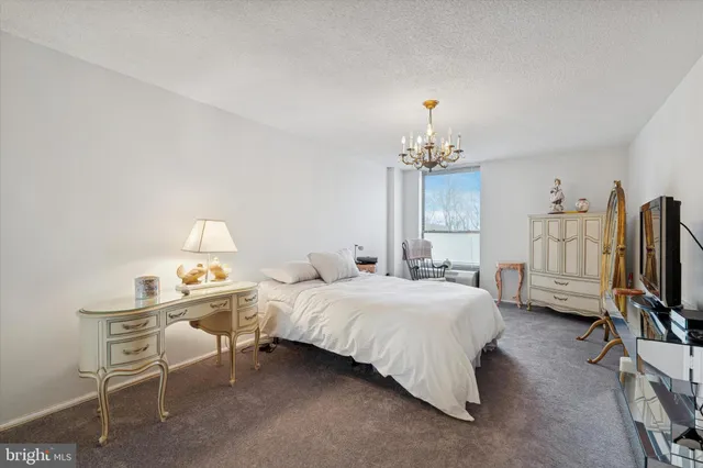 a bedroom with bed a chandelier and a flat tv