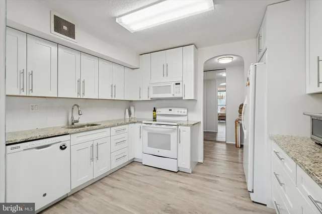 a kitchen with granite countertop white cabinets and white appliances
