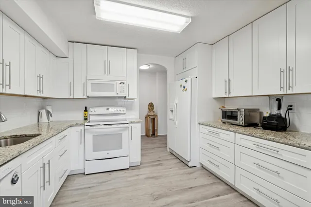 a kitchen with granite countertop white cabinets and white appliances