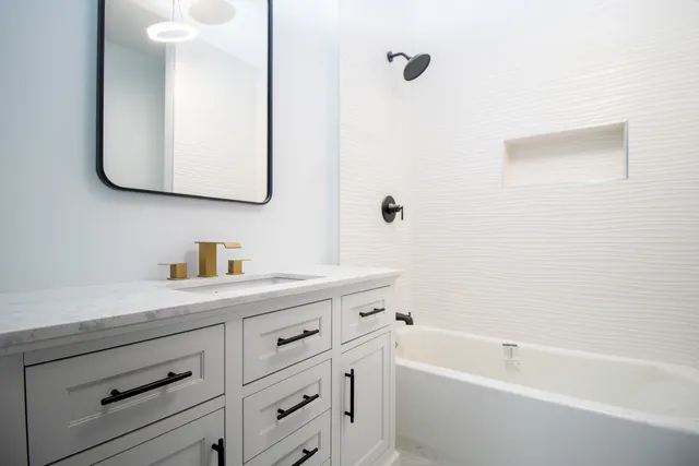 a bathroom with a tub sink and mirror