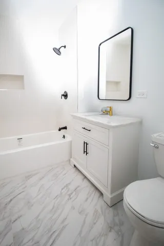 a bathroom with a toilet a sink a mirror and vanity