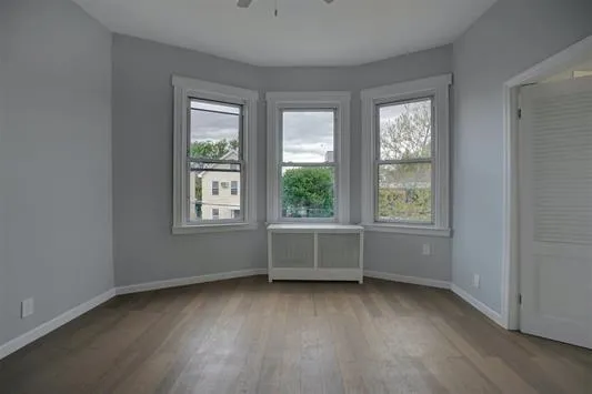 an empty room with wooden floor and windows