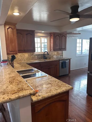 a kitchen with granite countertop a sink a counter space appliances and cabinets