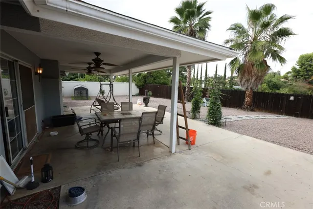 a view of a patio with a table and chairs under an umbrella with a small yard