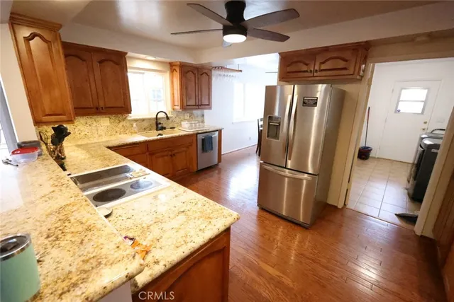 a kitchen with stainless steel appliances granite countertop a refrigerator a stove and a sink with wooden floor