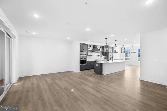 a open kitchen with kitchen island a sink dishwasher stove and white cabinets with wooden floor