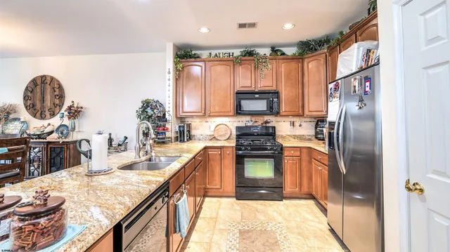 a kitchen with stainless steel appliances granite countertop a refrigerator a stove and a sink