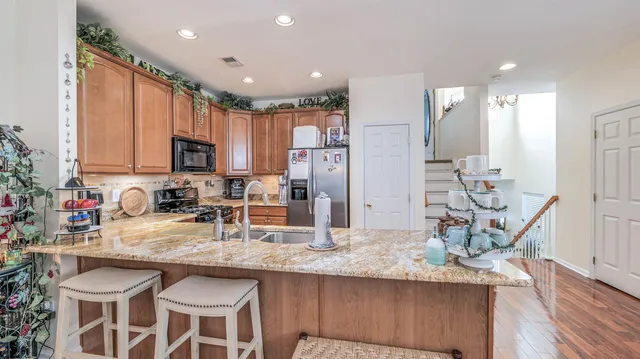 a kitchen with granite countertop a table chairs microwave and refrigerator