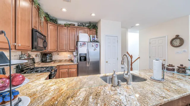 a kitchen with stainless steel appliances kitchen island granite countertop a refrigerator and a sink