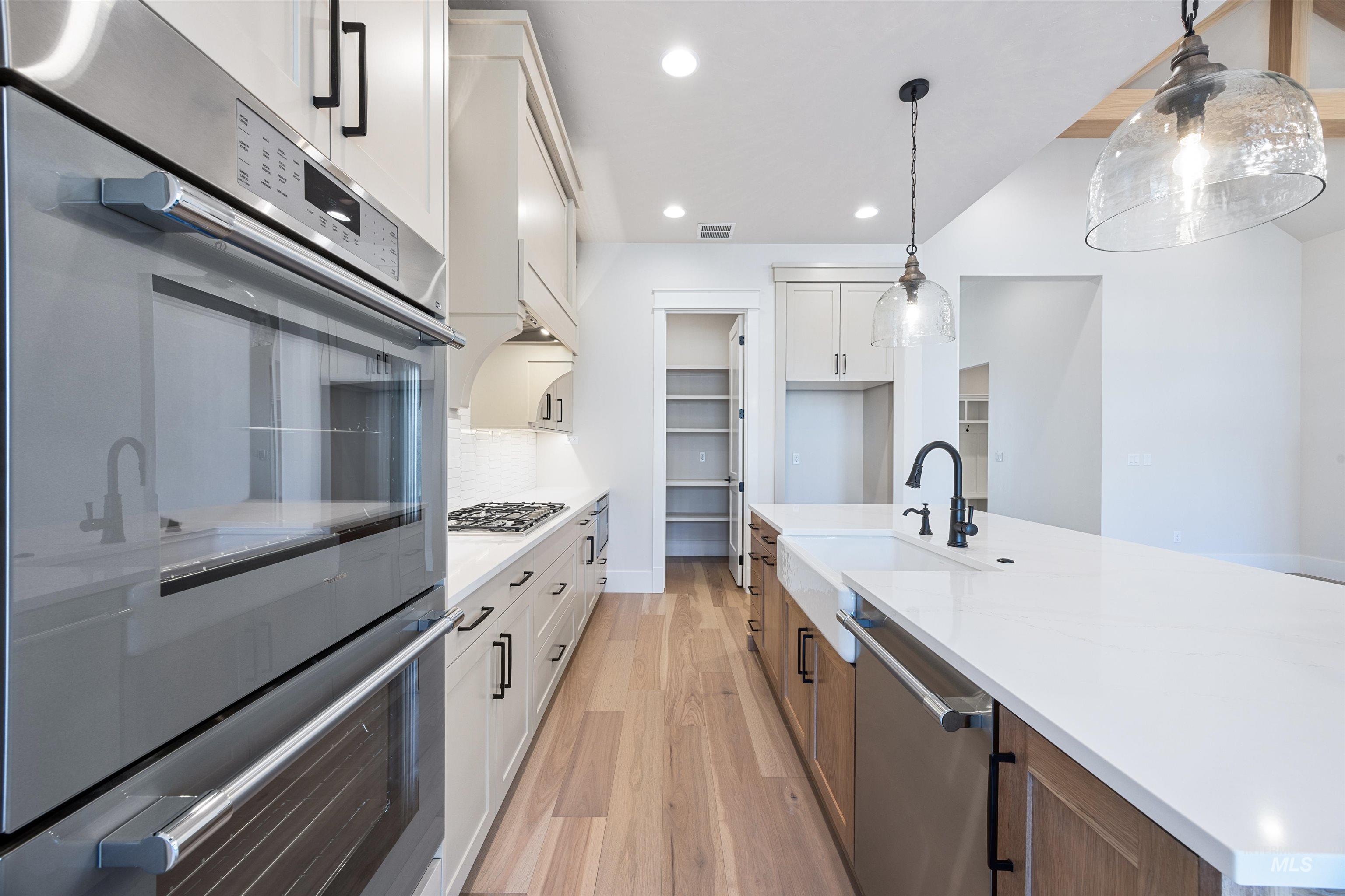 904 East Escalation Street Meridian, ID 83642 - Photo 15 of 36 Modern kitchen featuring a double wall oven, gas cooktop, and a large central island with a farmhouse sink