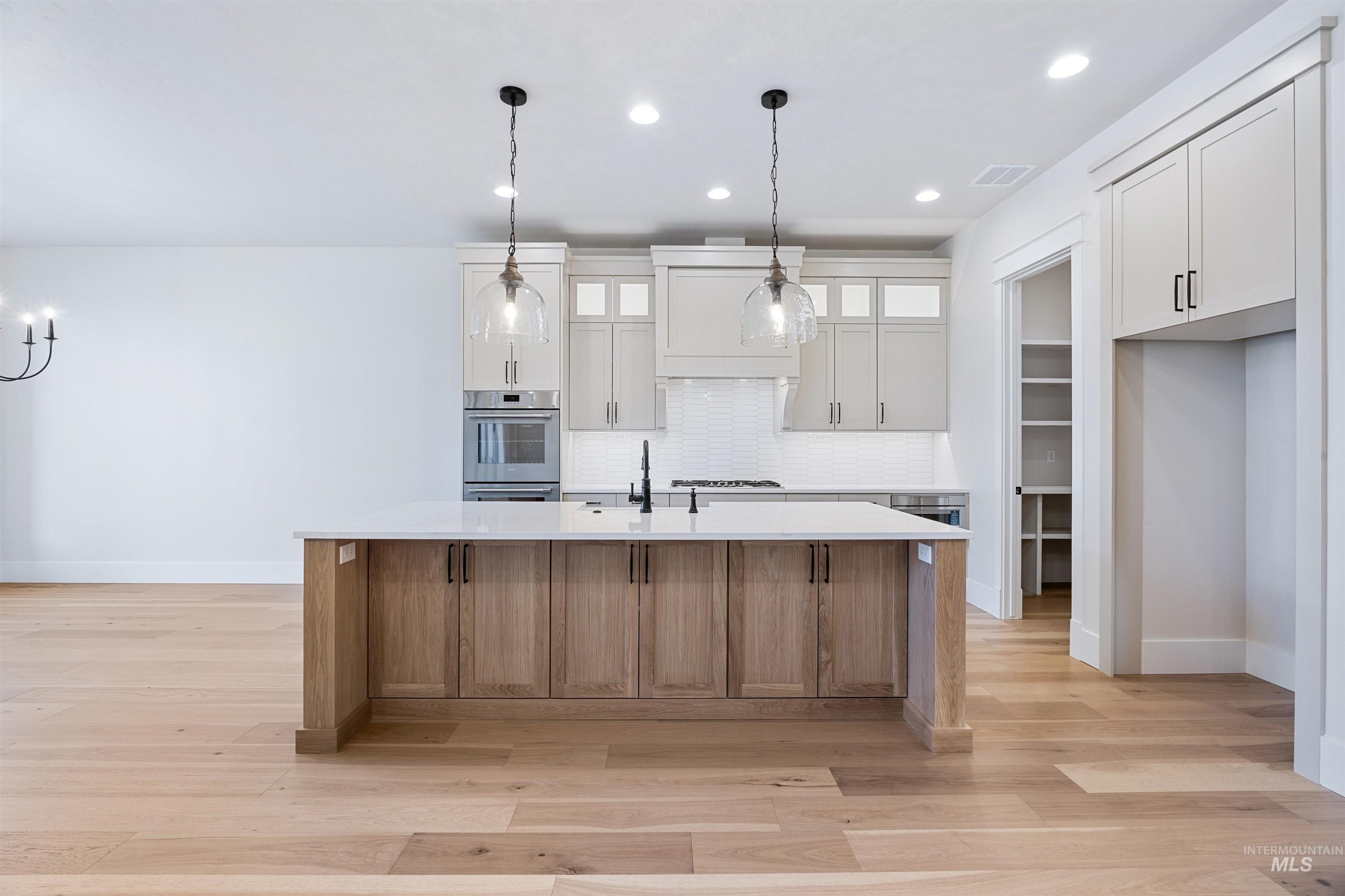 904 East Escalation Street Meridian, ID 83642 - Photo 18 of 36 Spacious kitchen featuring a central island with natural wood-finish cabinetry, white countertops, and contemporary pendant lighting