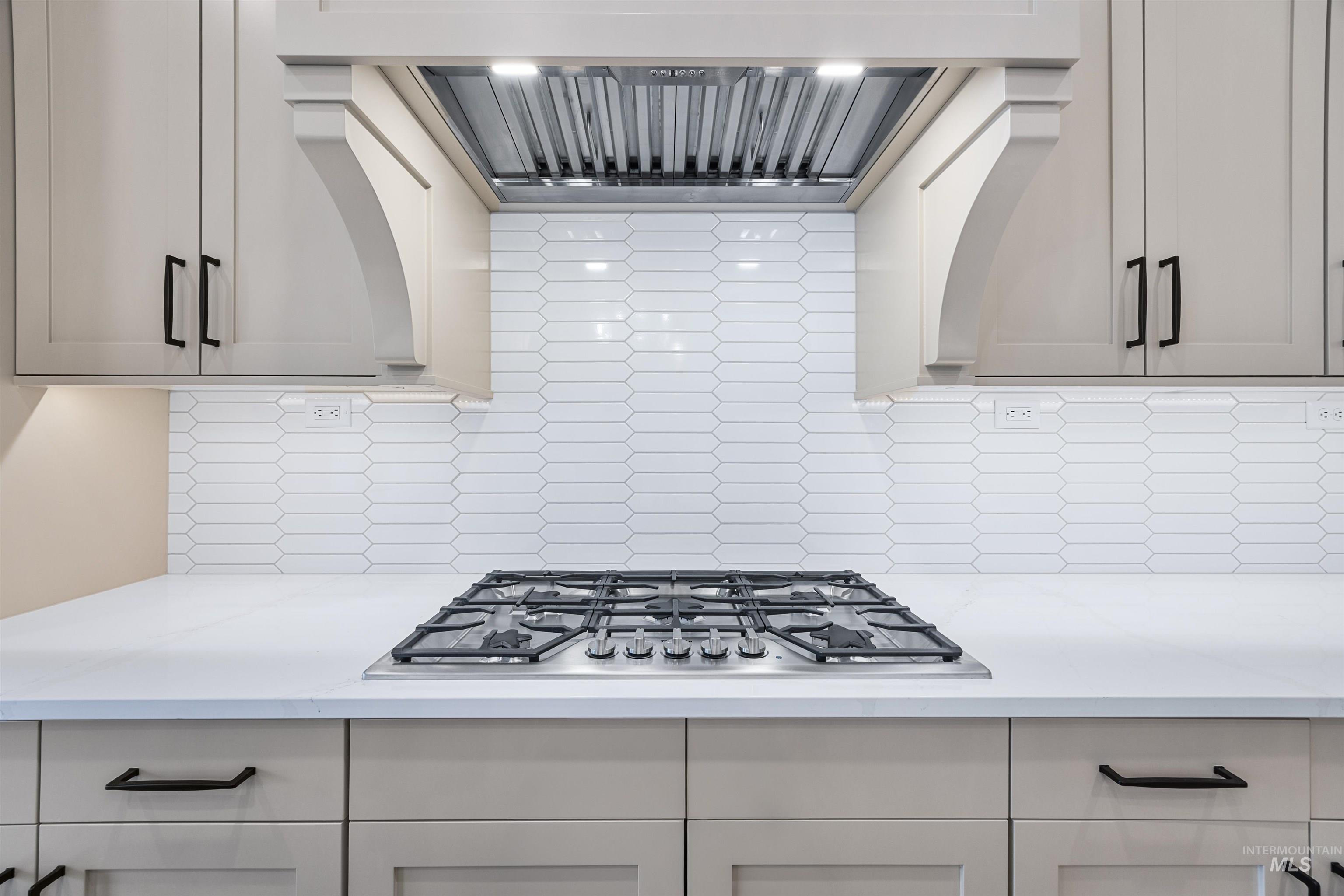 904 East Escalation Street Meridian, ID 83642 - Photo 23 of 36 Integrated stainless steel gas cooktop set within a light-toned countertop, complemented by a decorative range hood