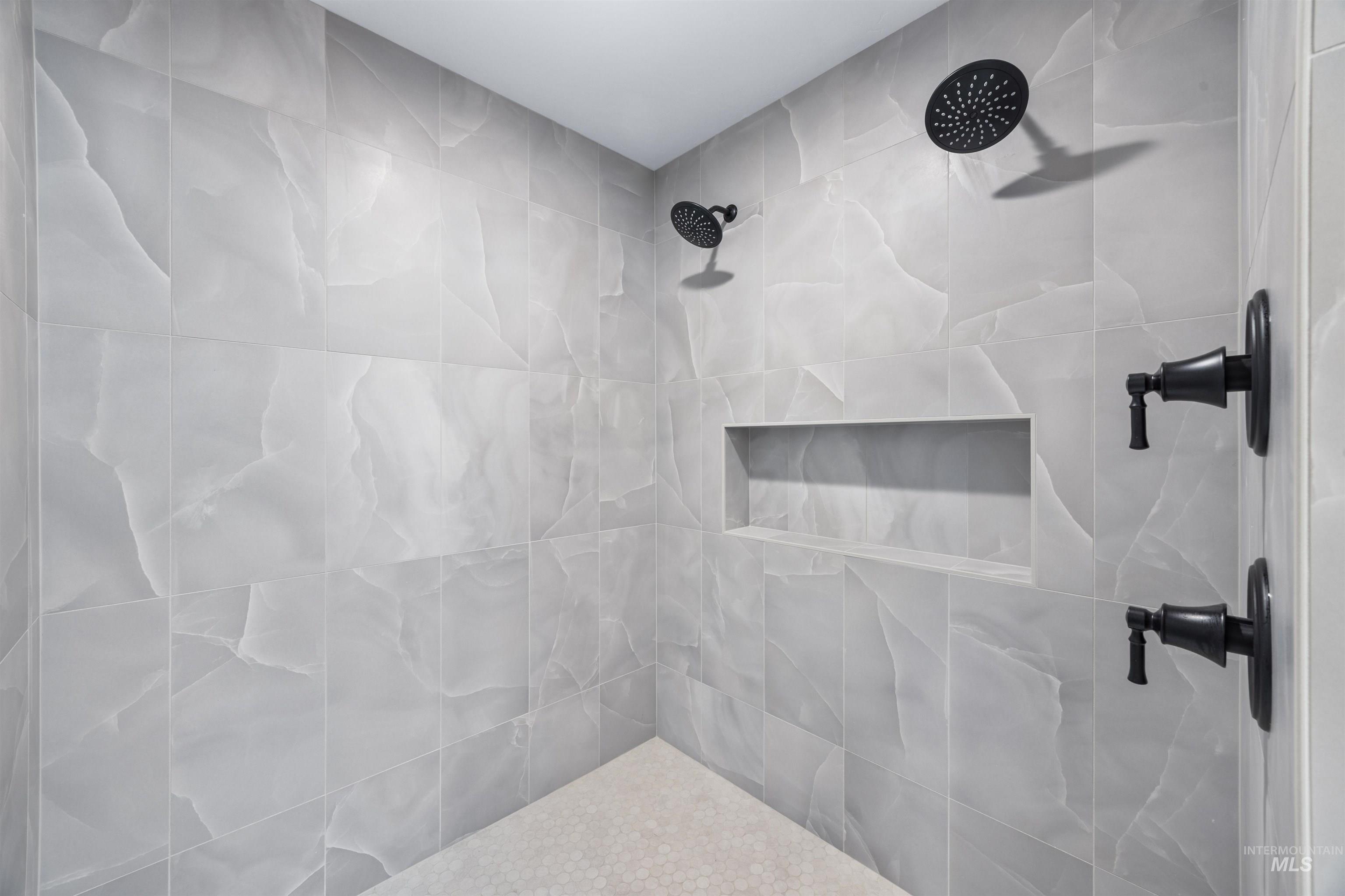 904 East Escalation Street Meridian, ID 83642 - Photo 30 of 36 Tiled shower with matte black fixtures, dual showerheads, an integrated niche, and a mosaic tile floor
