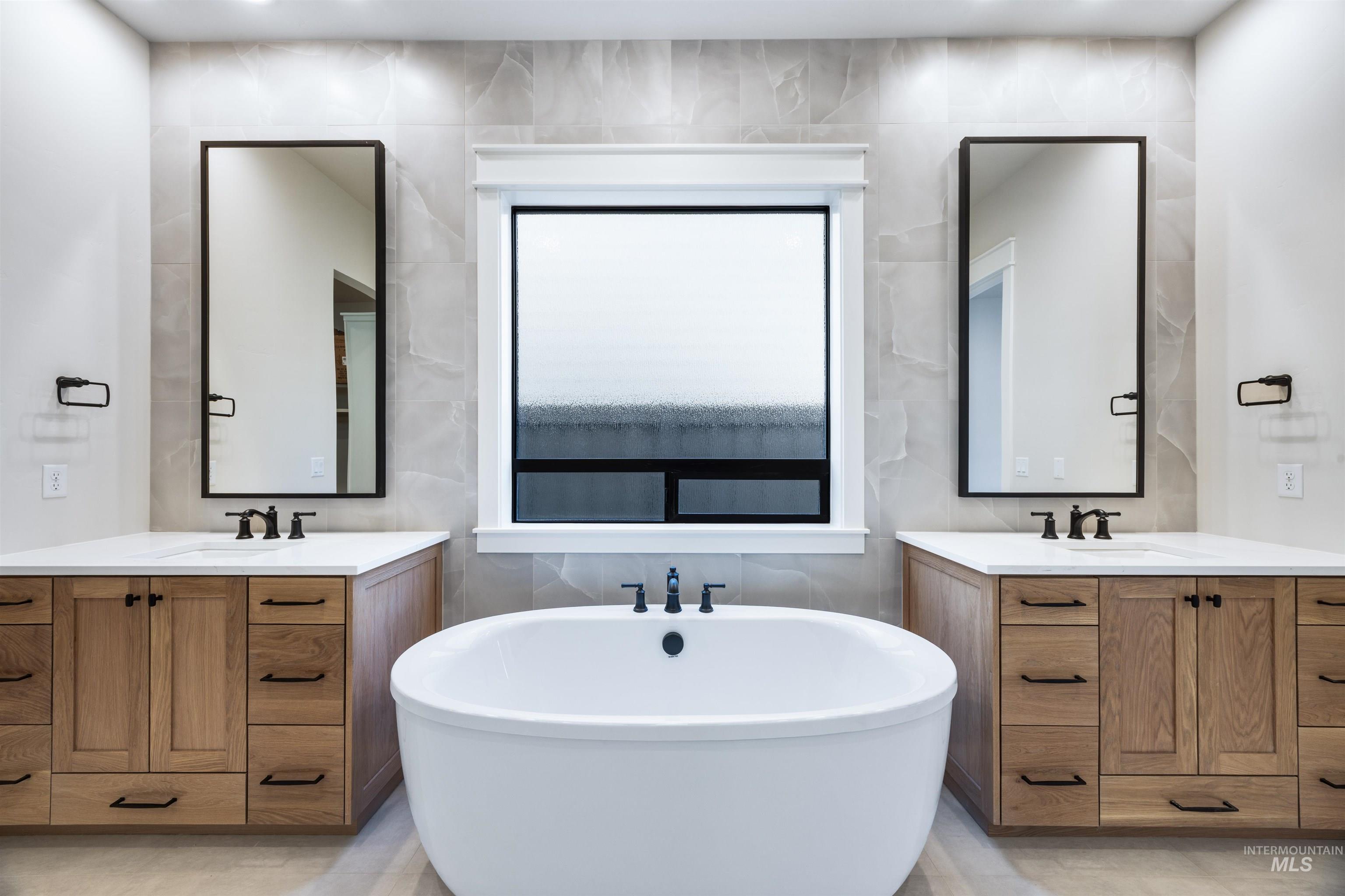 904 East Escalation Street Meridian, ID 83642 - Photo 31 of 36 Freestanding soaking tub centered between dual wood-finish vanities with light countertops and rectangular undermount sinks