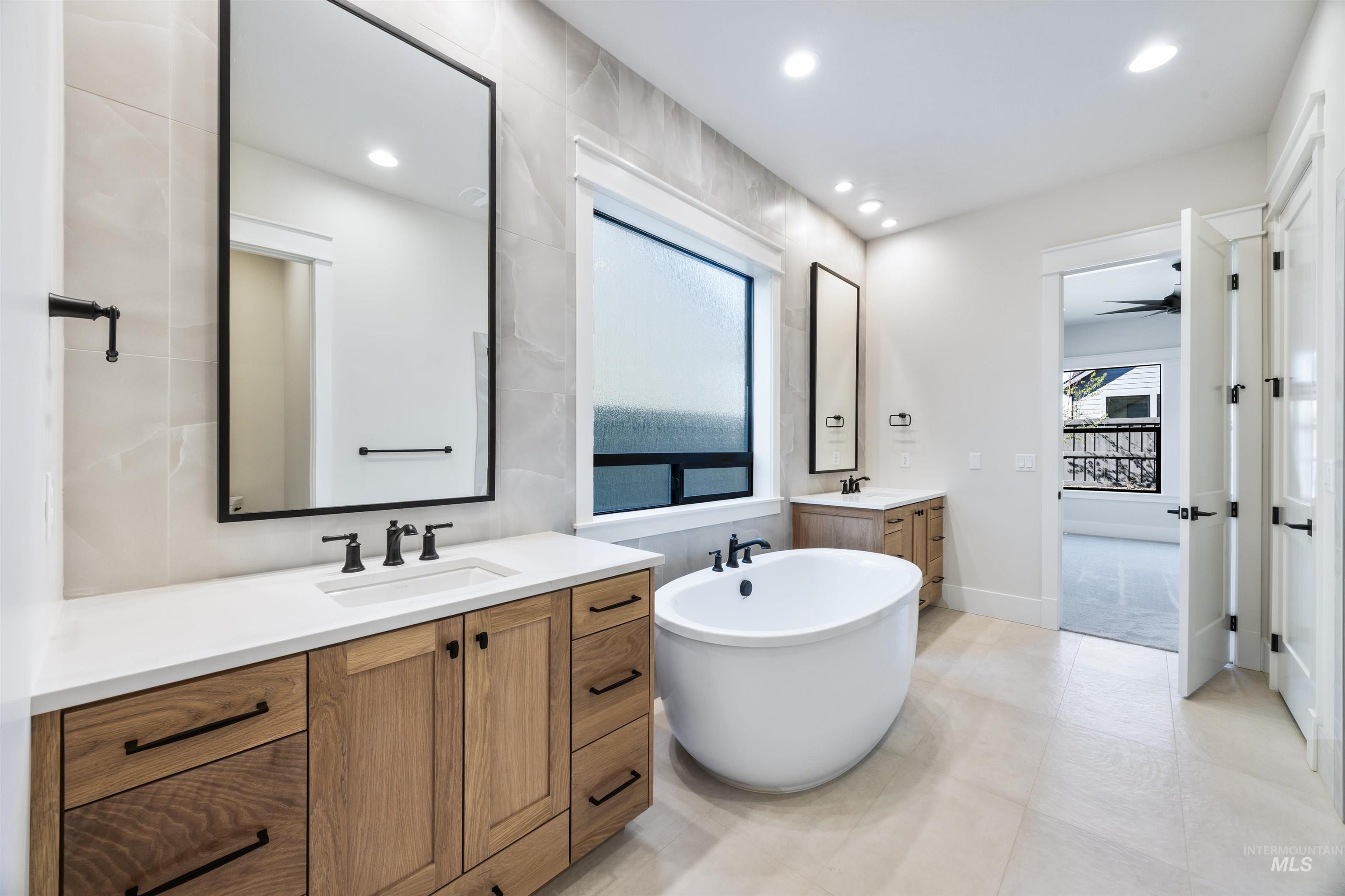 904 East Escalation Street Meridian, ID 83642 - Photo 32 of 36 Bathroom featuring a freestanding oval tub, dual wood-finish vanities with white countertops, matte black fixtures, and recessed lighting
