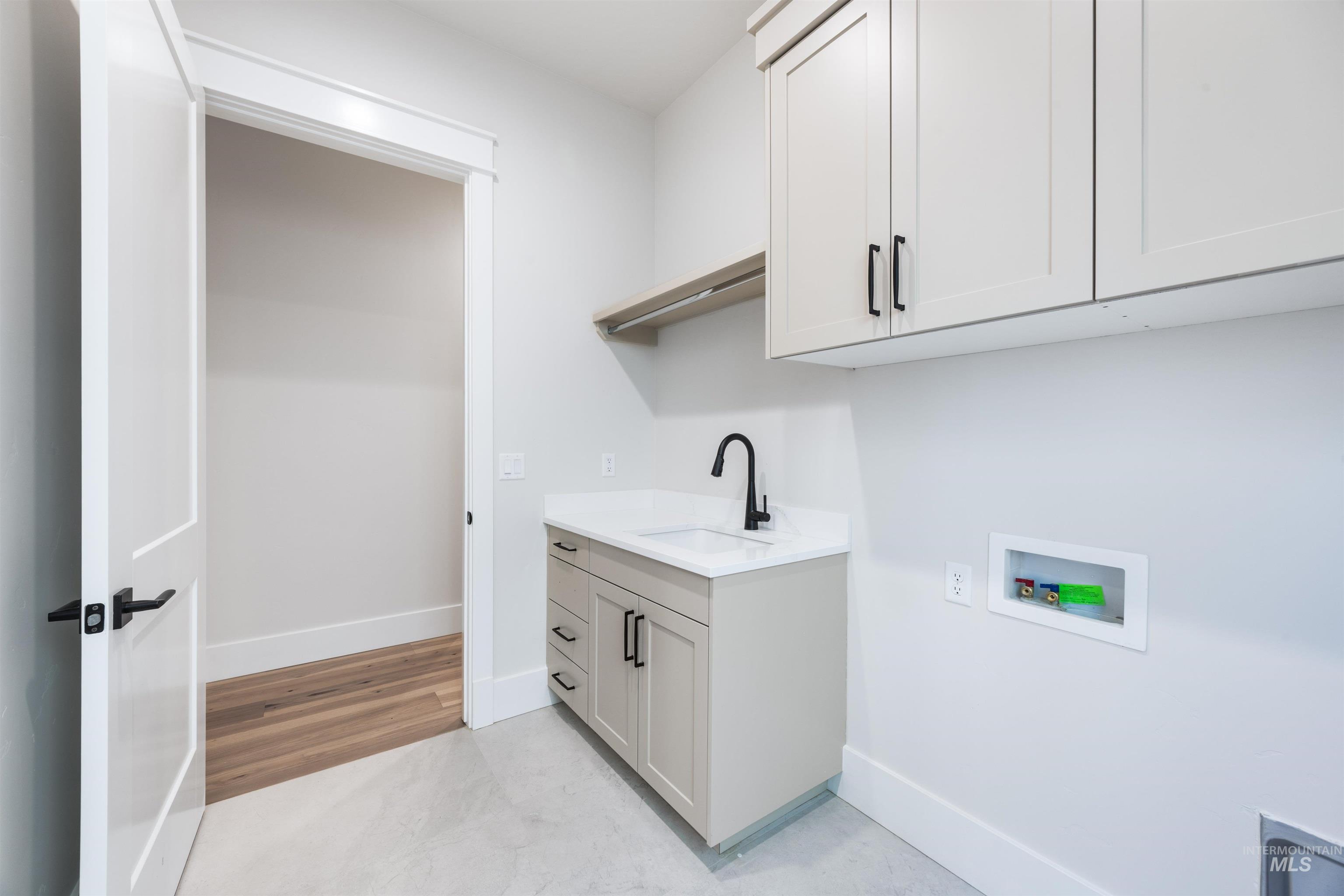 904 East Escalation Street Meridian, ID 83642 - Photo 34 of 36 Laundry room featuring light gray cabinetry, a white countertop with an undermount sink, and a matte black gooseneck faucet