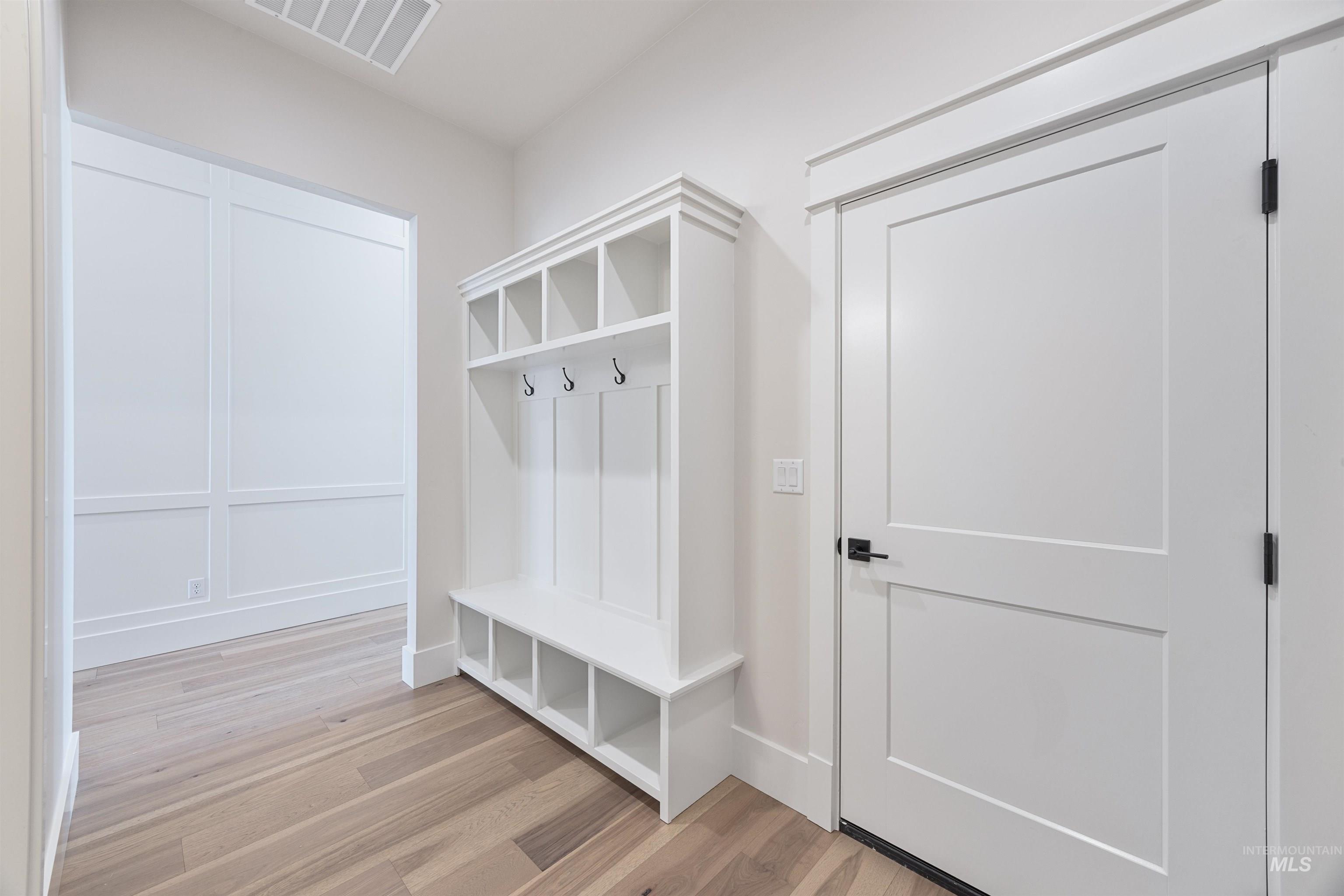 904 East Escalation Street Meridian, ID 83642 - Photo 35 of 36 Entryway featuring a built-in mudroom bench with cubby storage and coat hooks, wood-finish flooring, and a solid panel door with matte black hardware