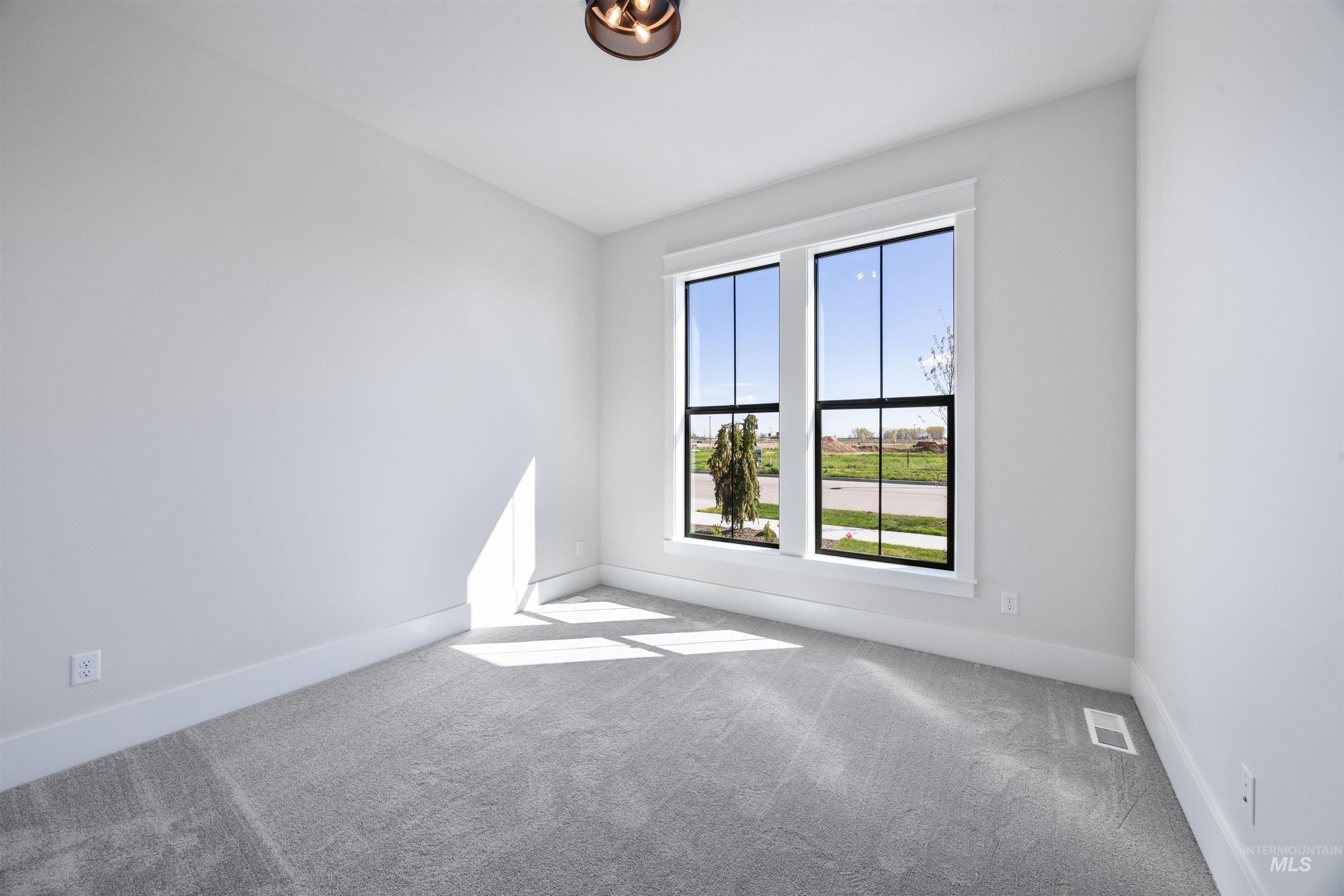 904 East Escalation Street Meridian, ID 83642 - Photo 4 of 36 Spacious room featuring broad windows with black framing, light gray carpeting, crisp white walls, and a contemporary ceiling fixture