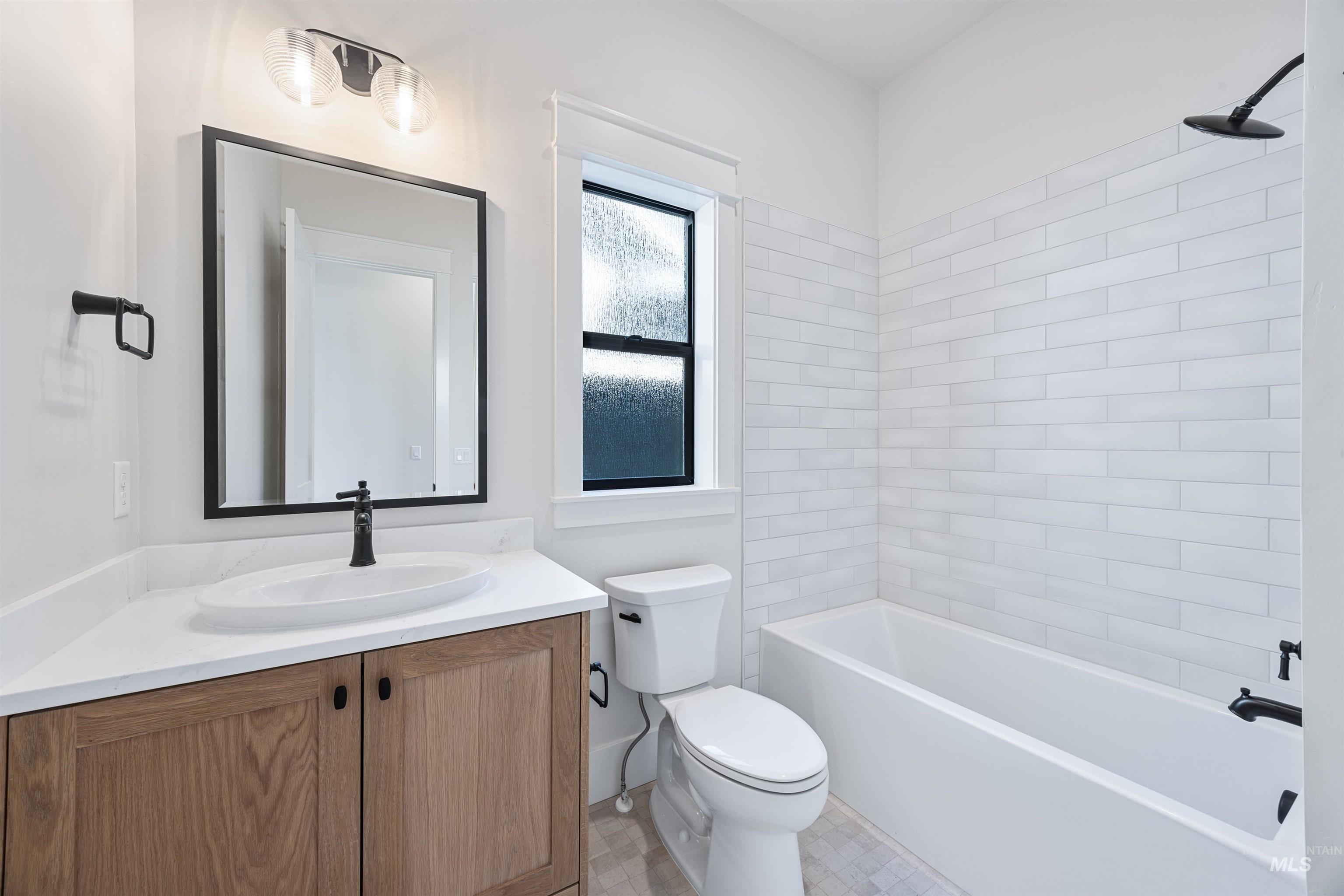 904 East Escalation Street Meridian, ID 83642 - Photo 6 of 36 Bathroom featuring a wood-finish vanity with a white countertop, a rectangular undermount sink, and black fixtures