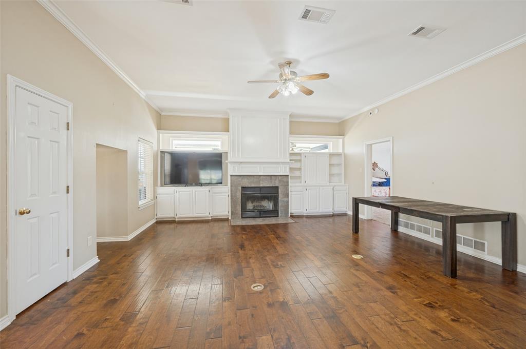 1601 East Blackjack Road East Pilot Point, TX 76258 - Photo 5 of 30 Hardwood flooring throughout, crown molding, built-in cabinetry, fireplace with stone surround, and ceiling fan