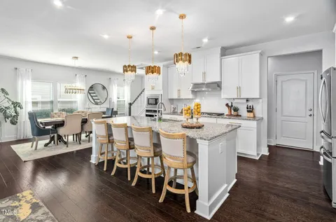 a living room with furniture a potted plant and a kitchen view