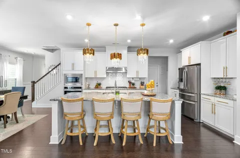 a kitchen with stainless steel appliances kitchen island granite countertop a stove a sink and a refrigerator