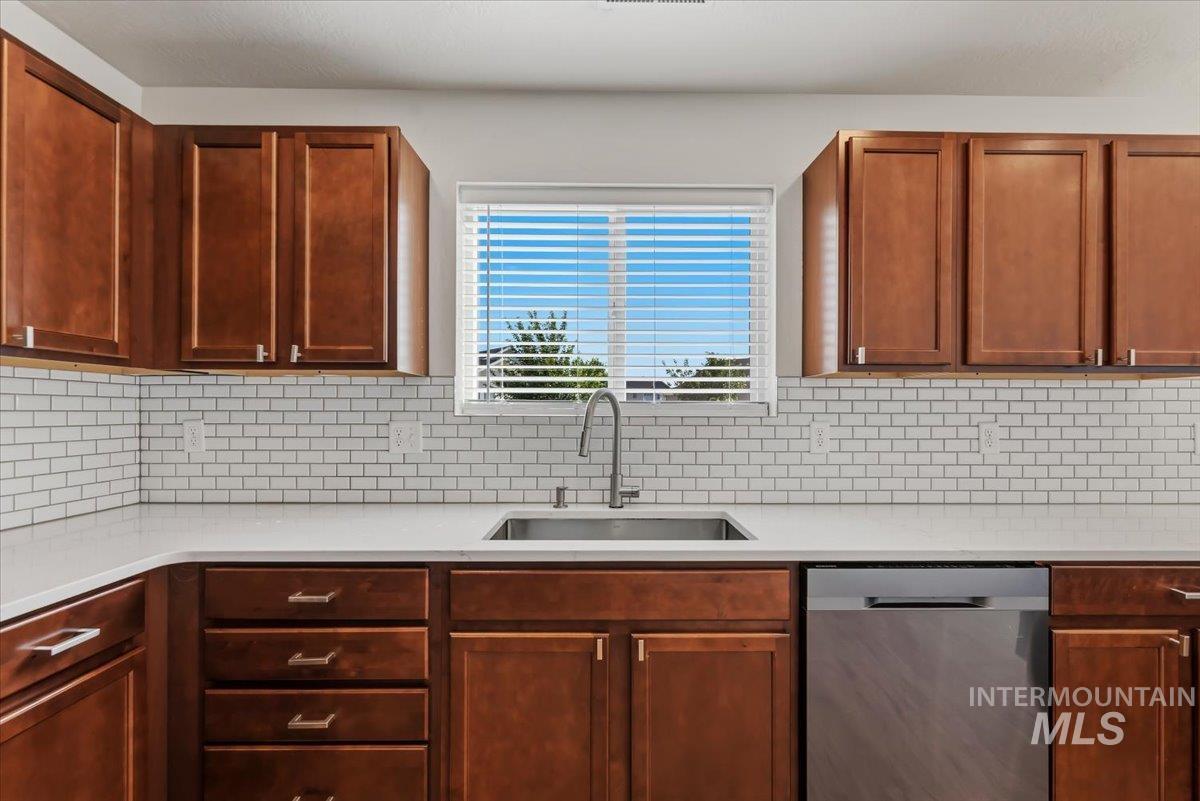 12310 West Hidden Point Drive Star, ID 83669 - Photo 9 of 48 Kitchen featuring wood cabinetry, white subway tile backsplash, light-toned countertops, and a stainless steel sink with a modern faucet