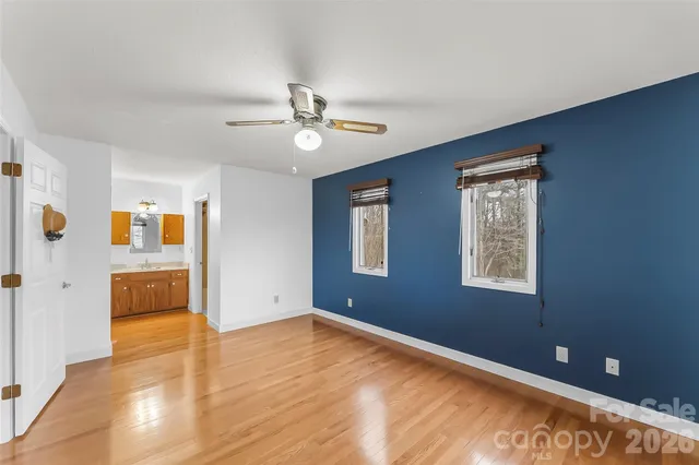 a view of an empty room with window and wooden floor