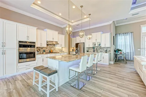 a large kitchen with stainless steel appliances granite countertop a stove oven and a white cabinets