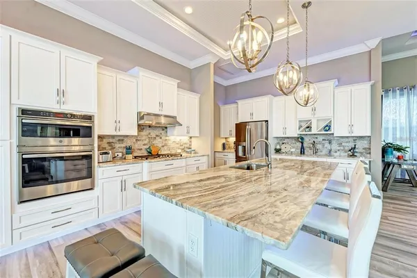 a large kitchen with stainless steel appliances granite countertop a stove oven and a view of living room