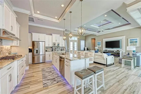 a kitchen with stainless steel appliances granite countertop a refrigerator stove a sink and white cabinets
